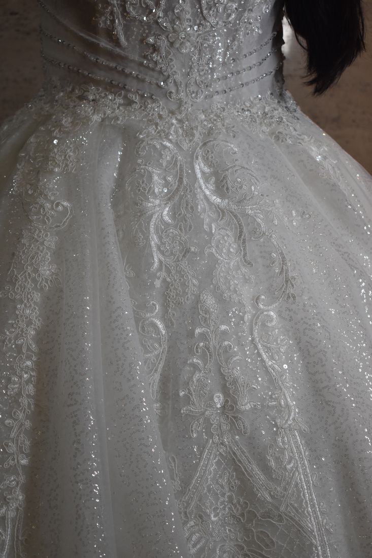 Close-up of corded lace, sequins and crystal beadwork on a bridal skirt